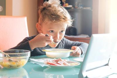 Blond boy eating breakfast and watching the table Blond boy eating breakfast and watching the table