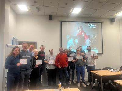 A group of potential foster carers pose in a group and smile at the camera while attending a Skills to Foster Training Session with Foster North East