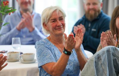 Lynne - a foster carer with short hair is smiling and clapping